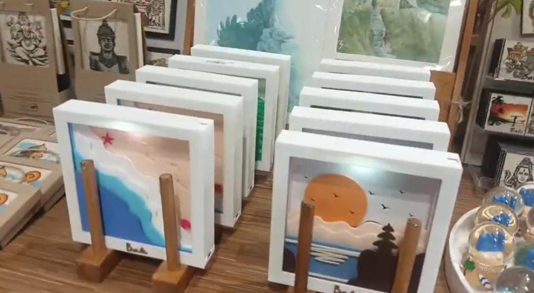 Our booth: rows of white 3D frames on wooden stands, beach and sunset scenes in front