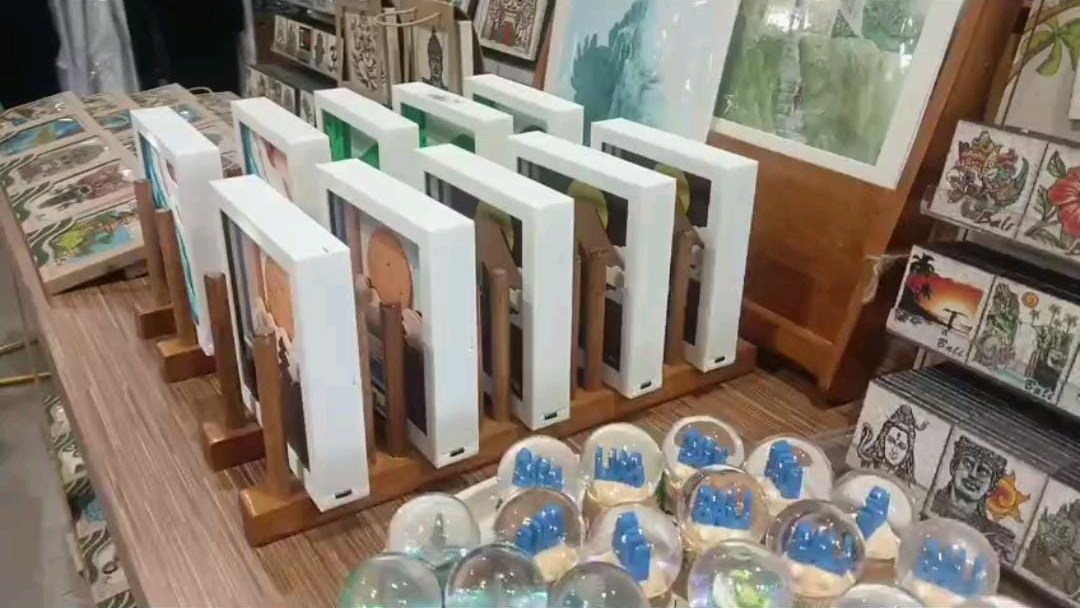 A long row of white 3D frames on teak stands with snow globes in front