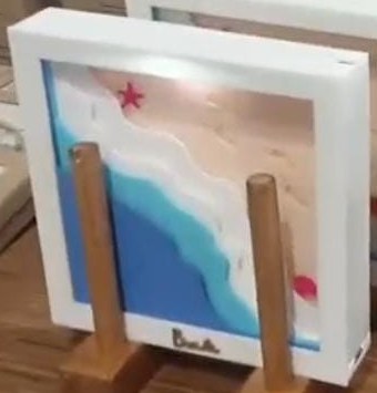 White 3D frame with layered turquoise waves rolling onto a sandy beach and a red starfish